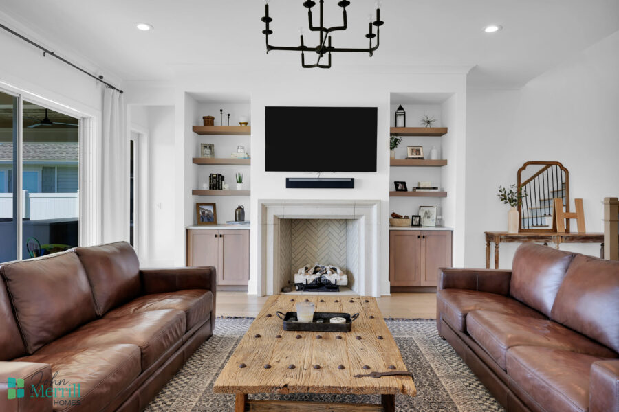 Bright living room featuring a fireplace, wall-mounted TV, and built-in shelves filled with decorative items and books.