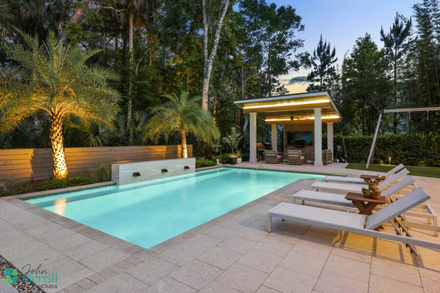 Luxurious outdoor swimming pool surrounded by lush greenery and palm trees, featuring a shaded cabana and comfortable lounge chairs for relaxing evenings.