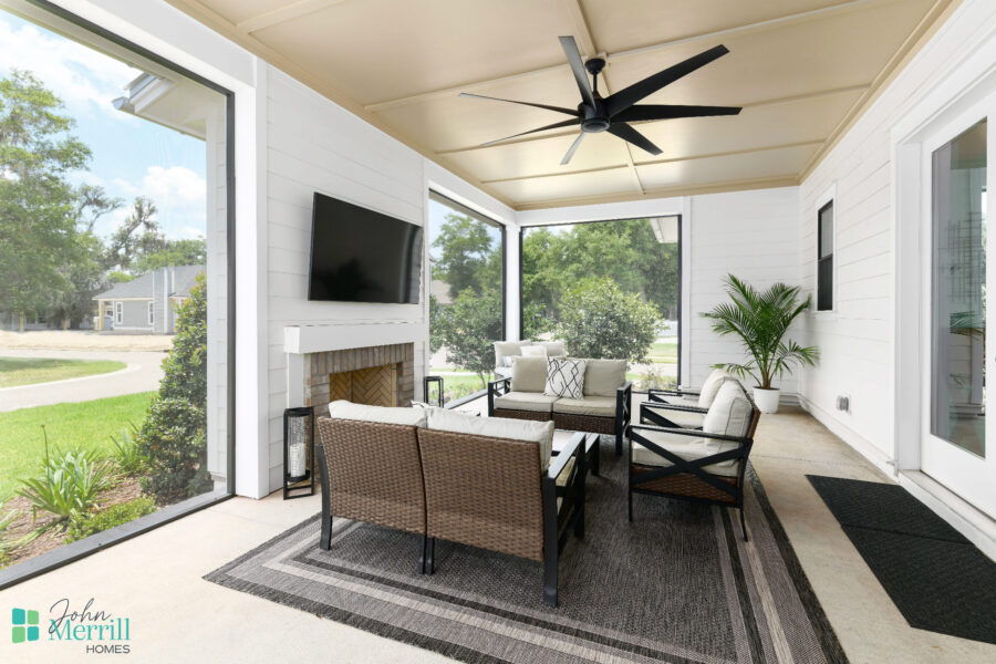 Bright and inviting screened porch featuring comfortable outdoor furniture, a ceiling fan, and large windows that offer scenic views of the surrounding greenery.