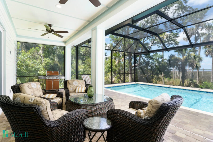 A spacious outdoor living space featuring a screened enclosure, comfortable wicker furniture, and a swimming pool, perfect for relaxing and entertaining in a private backyard setting.