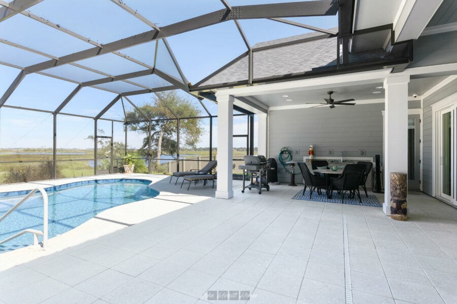 Comfortable screened-in backyard with a sparkling pool, outdoor dining area, lush scenery, and a shaded patio perfect for relaxing and entertaining.