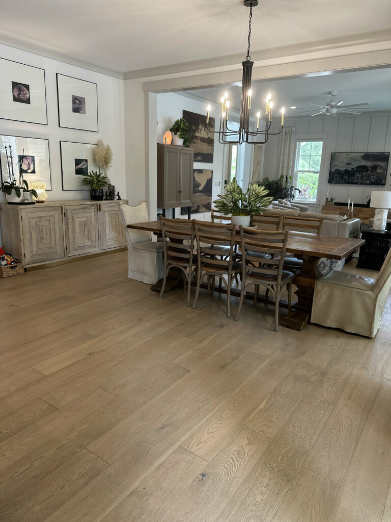 1. Bright open-concept dining and living area with hardwood flooring, modern chandelier, and elegant decor, showcasing stylish furniture and natural light from large windows.