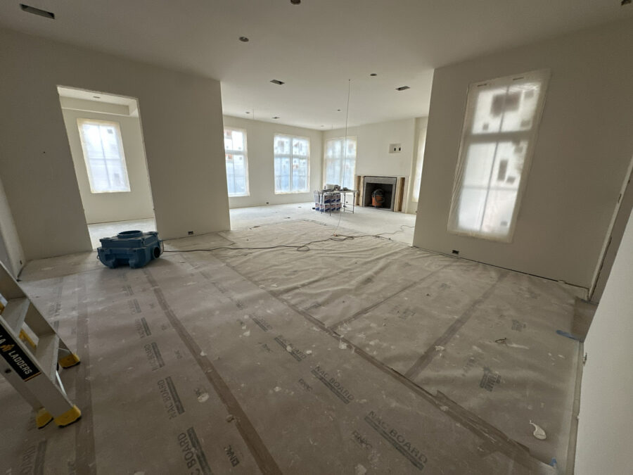 Spacious living room under construction with large windows, neutral walls, and an unfinished fireplace, showcasing modern interior design and upcoming home finishes.