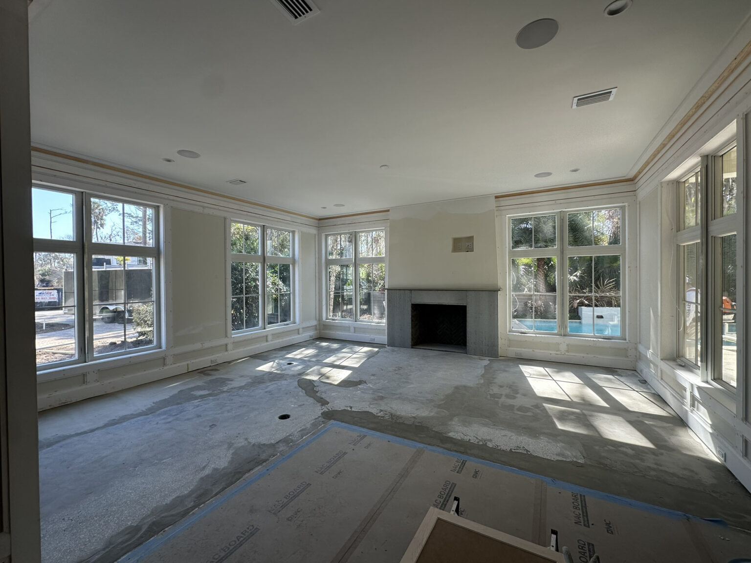 Spacious living room featuring large windows, a central fireplace, and abundant natural light, perfect for family gatherings and relaxation.