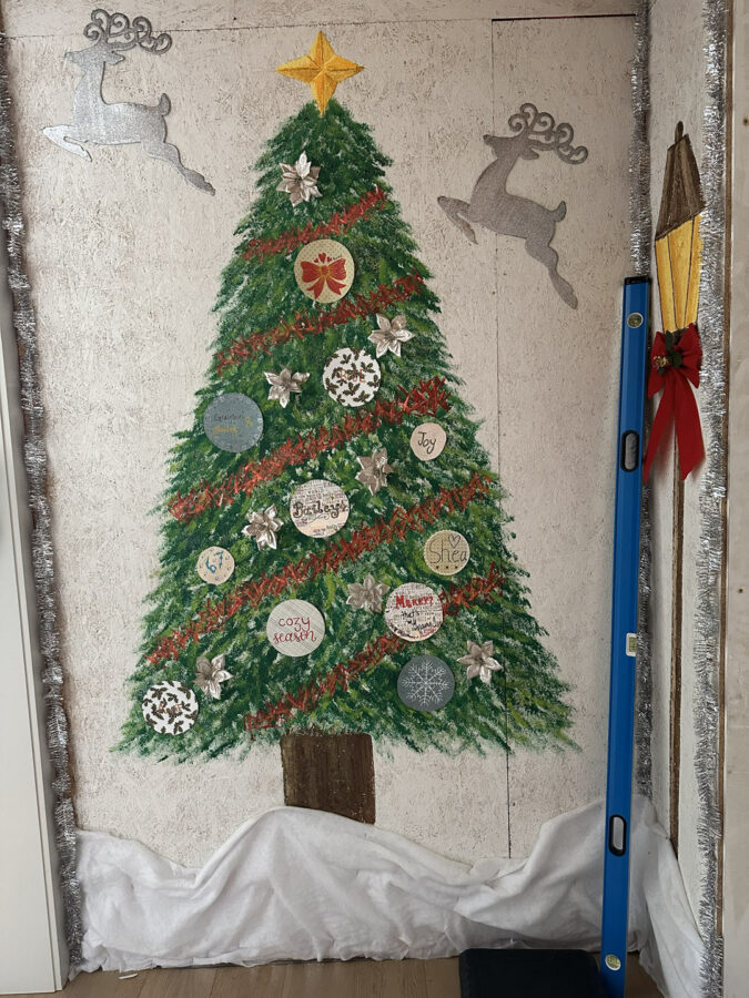 Colorful decorated Christmas tree on wall with ornaments and stars during holiday season, featuring festive-themed designs and personalized messages.