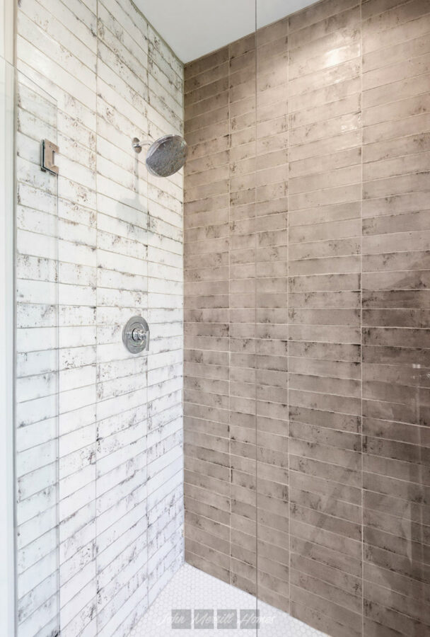 Renewed wood-look tile shower with a glass door and modern fixtures, showcasing a stylish, durable design perfect for luxury home bathrooms.
