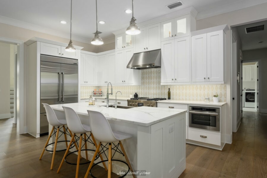 Bright modern kitchen with white cabinets, marble countertops, stainless steel appliances, and pendant lighting. Perfectly designed for cooking and entertaining.