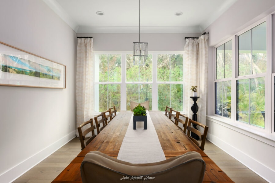 Modern dining room with large windows, wooden table, light-colored walls, and elegant decor, perfect for family gatherings and entertaining guests.