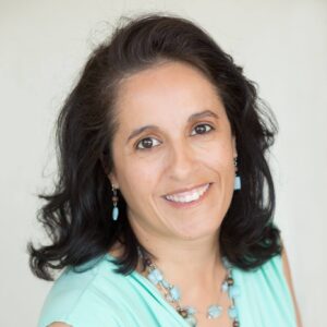 Elegant woman smiling with dark hair and turquoise jewelry.