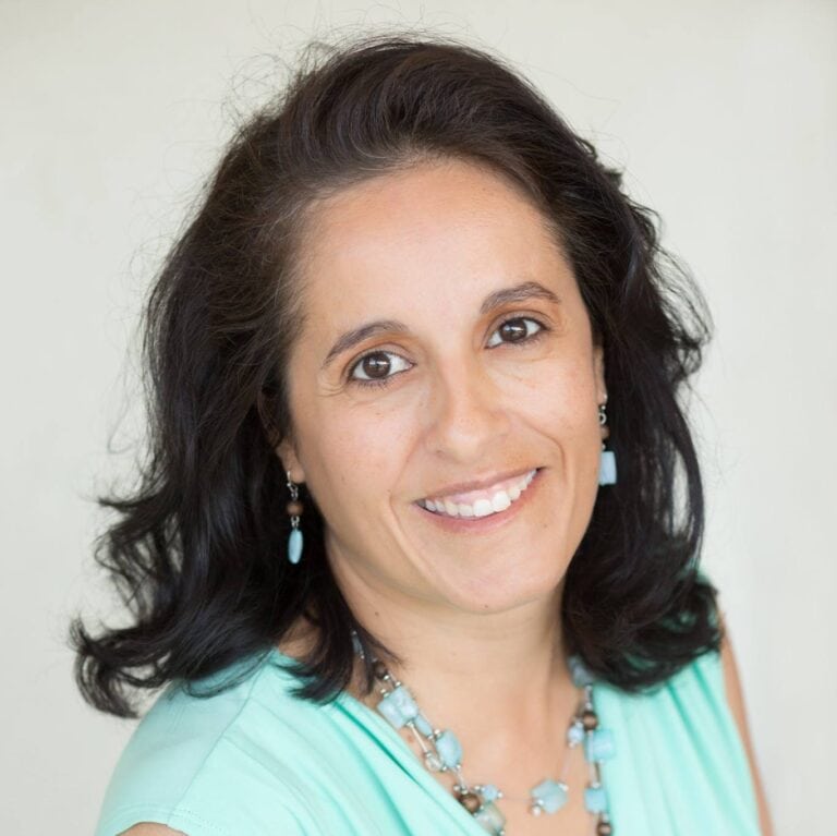 Elegant woman smiling with dark hair and turquoise jewelry.