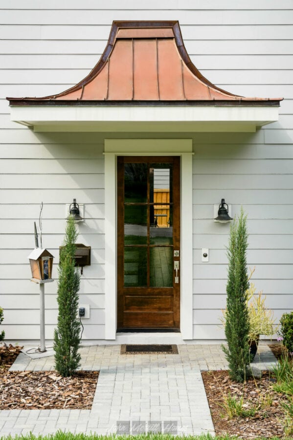 Garden home exterior with modern front door, pathway, and greenery, showcasing attractive curb appeal with stylish lighting and landscaping.
