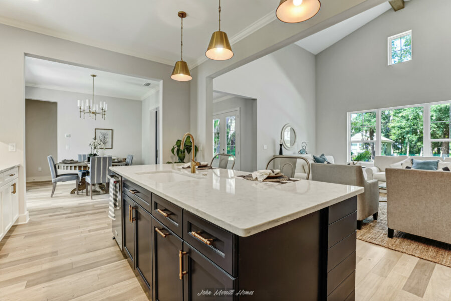 Modern open-concept kitchen and living room with large windows, bright natural light, and stylish decor in a newly built home.