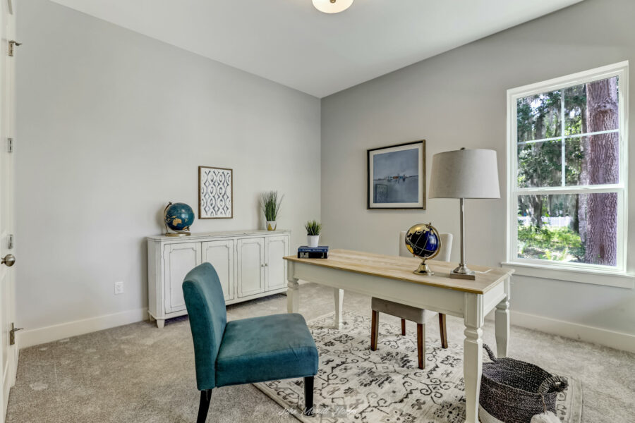 Modern home office with white walls, a large window, a white desk with decorative globes, and comfortable chairs creating a bright and inviting workspace.