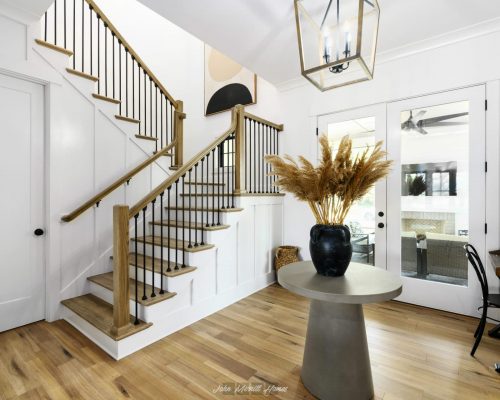 Modern staircase with wooden steps and black railing in a bright, stylish home interior.
