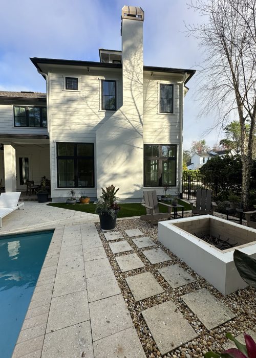 Beautiful modern white house featuring large windows, a backyard pool, and a cozy fire pit area, perfect for outdoor living and entertaining.