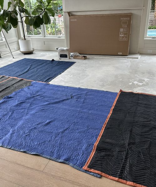 New home construction interior with floor protection, tools, and large windows providing natural light.