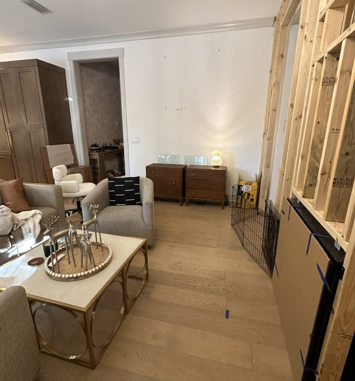 1. Bright living room in a newly constructed home with unfinished wall space, wooden flooring, and modern furniture, showcasing ongoing interior renovation.