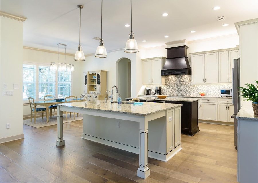 Spacious modern kitchen with white cabinets, granite countertops, and a large island for cooking and dining.